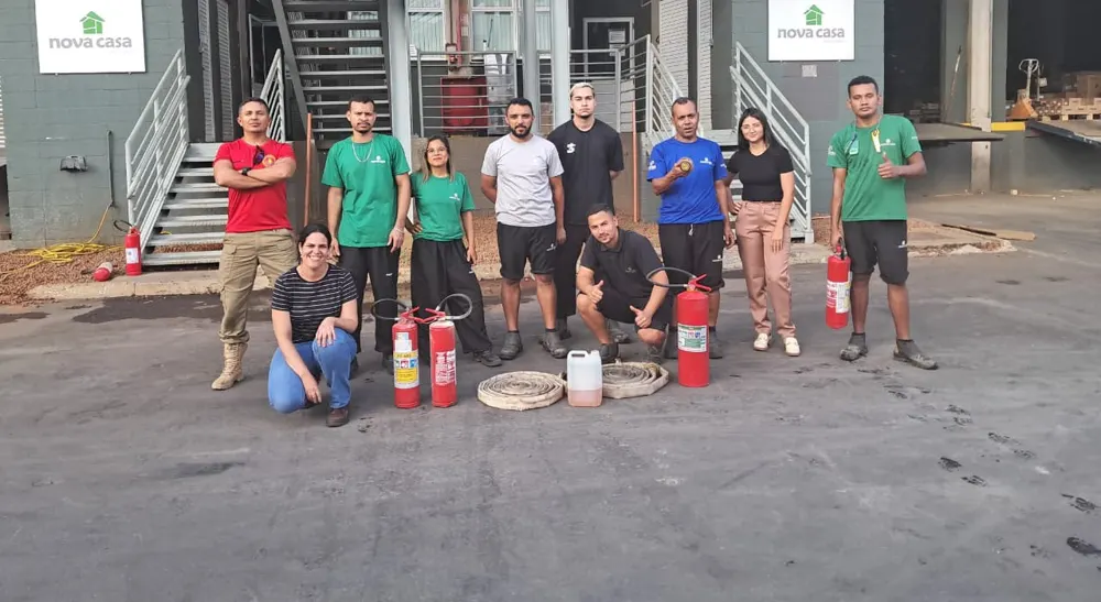 Turma da Nova Casa Distribuidora com extintores e mangueiras após o treinamento de brigada